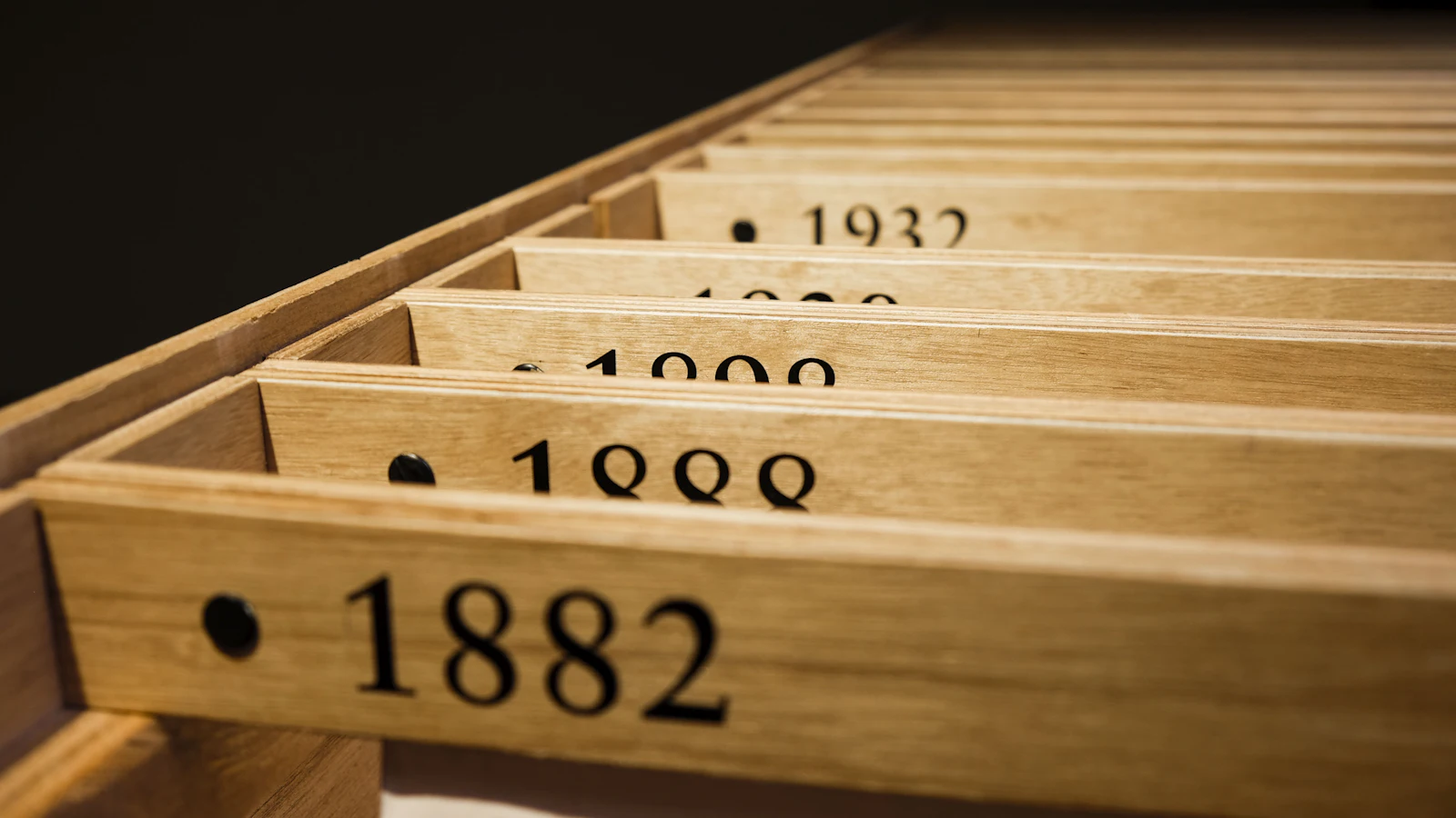Numbered wooden drawers set into one cabinet, 1882, 1888, 1909 and 1932, each a separate compartment in a shared frame, the way each agent gets its own worktree in one repository