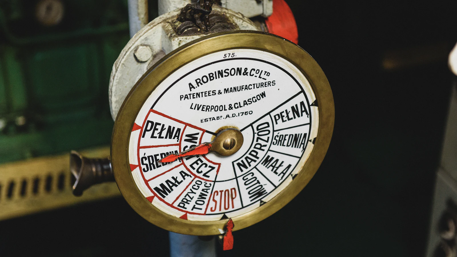 A brass engine-order telegraph by A. Robinson & Co. with ahead, astern and a red STOP on one dial: the bridge sets the direction, including when to stop